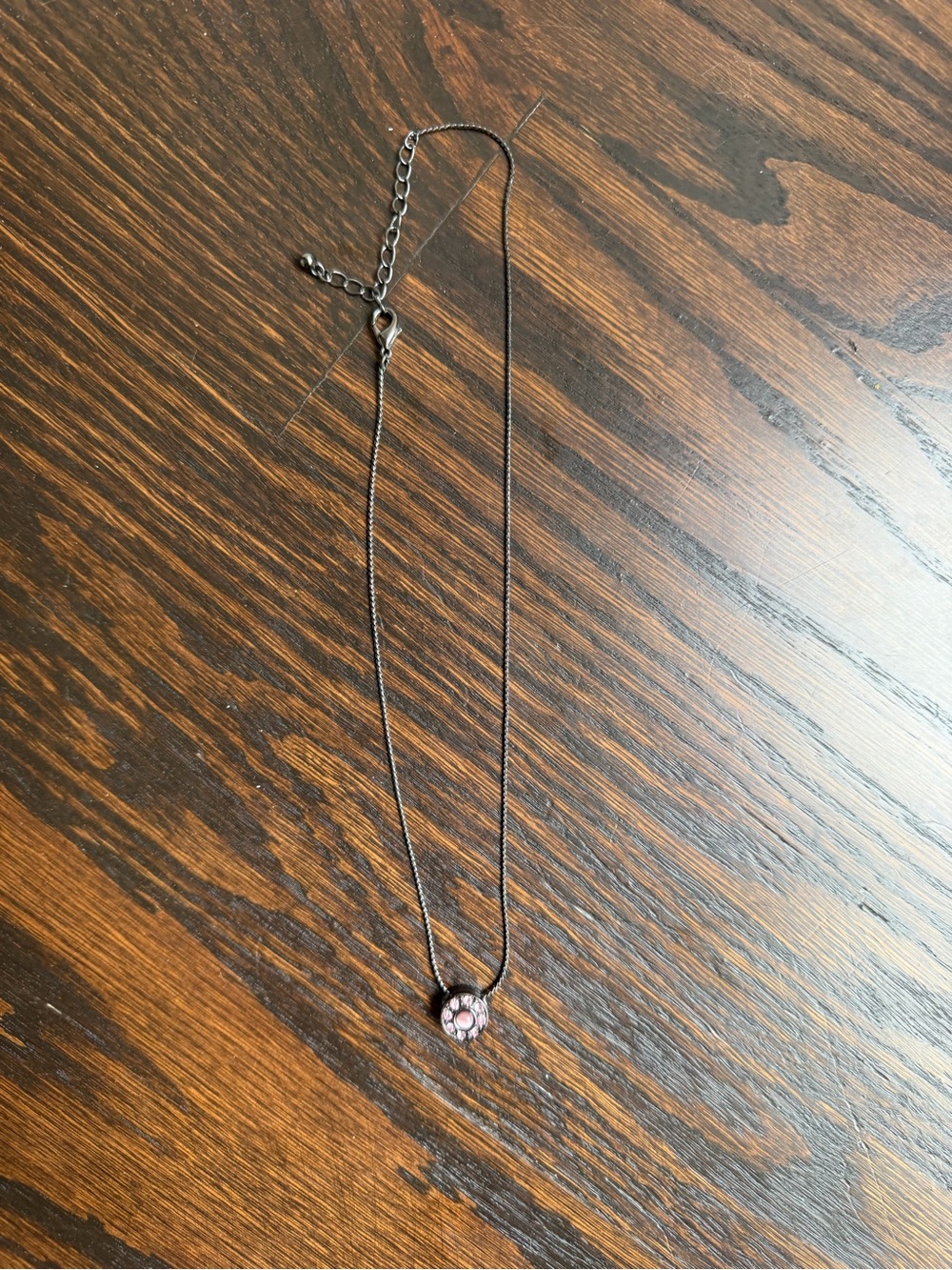 Dark-toned chain necklace with a round pink stoned pendant